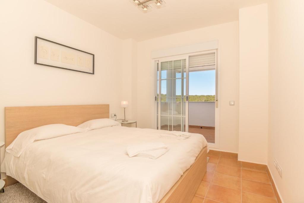 biała sypialnia z dużym łóżkiem i oknem w obiekcie 2167-Superb 2 bedrooms in luxury complex with pool w mieście La Alcaidesa
