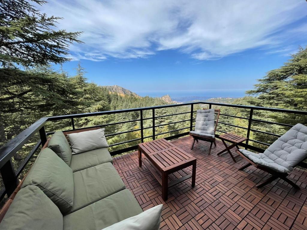 a balcony with two chairs and a wooden table and chairs at Cedar Scent Guesthouse in Batroûn