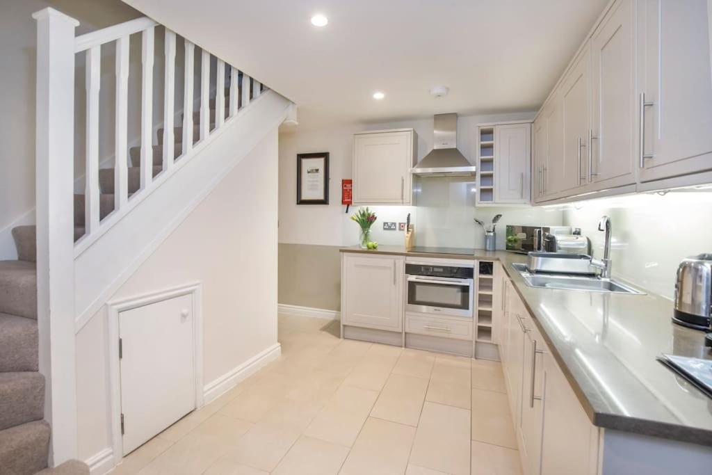 a kitchen with white cabinets and a staircase at The Wesley in York