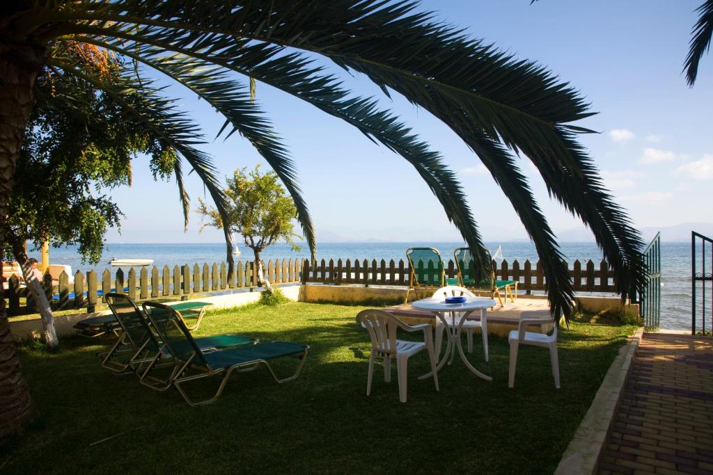 una mesa y sillas bajo una palmera cerca del océano en Evgenios Studios, en Kavos