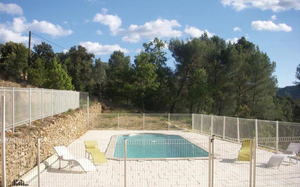 une piscine avec des chaises et une clôture dans l'établissement Le bastidon des tilleuls, au Beausset