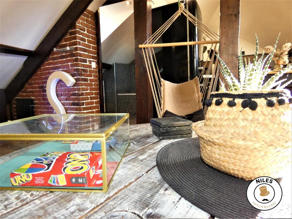 a table with a hat and a glass box and a basket at La Caze Paloise ~ Atypique ~ 100% Fonctionnel in Pau