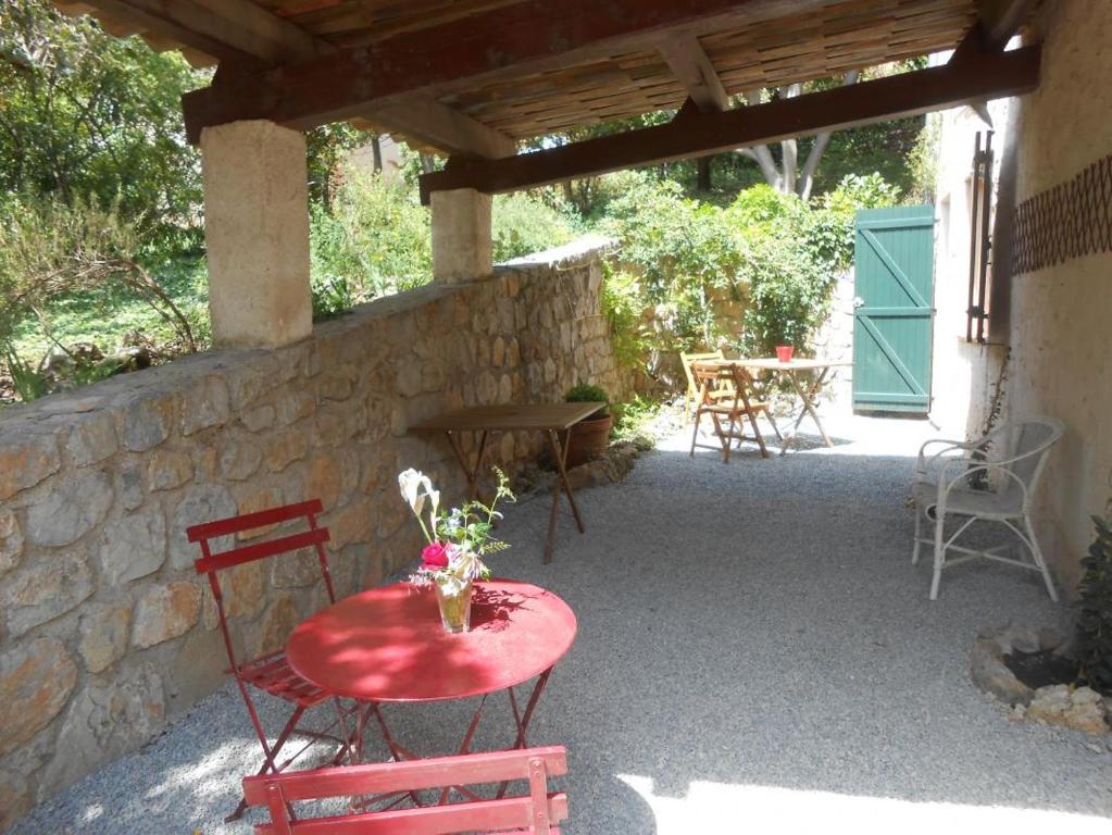 un patio avec une table et des chaises rouges et un mur en pierre dans l'établissement Gite de tournon, à Montauroux
