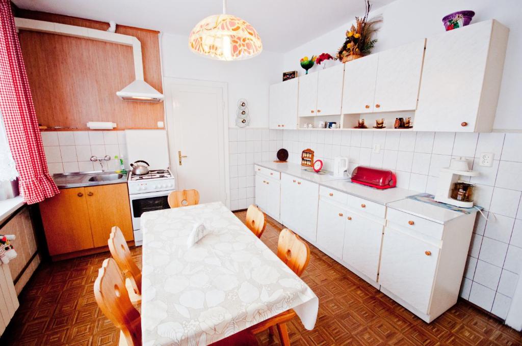 una cocina con armarios blancos y una mesa con sillas. en Willa Wanda, en Zakopane