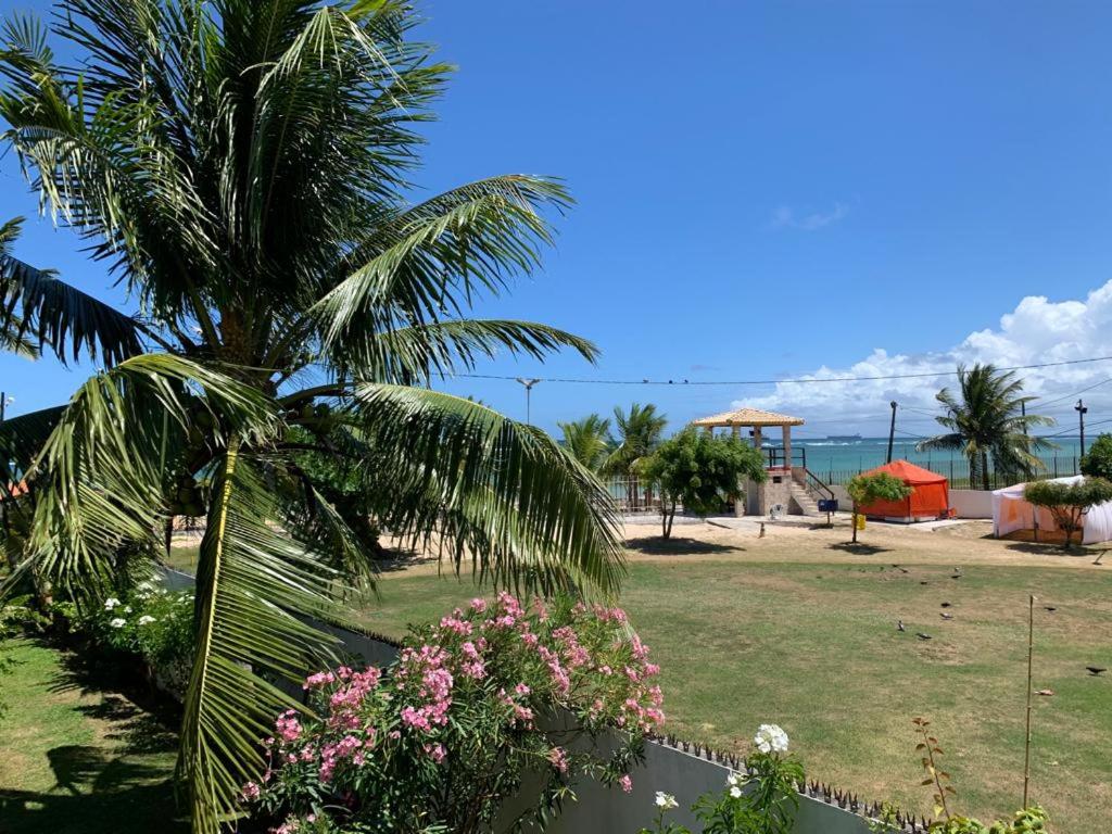 uma palmeira sentada ao lado de um parque com flores em apartamento de frente para o mar em Vera Cruz de Itaparica