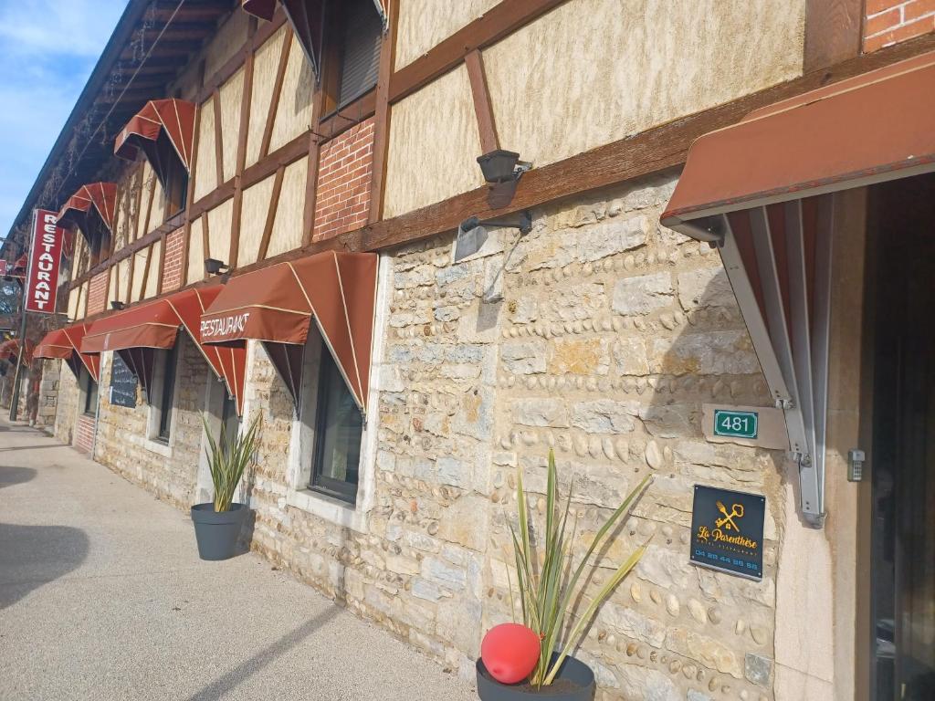 a stone building with plants in front of it at Hôtel La Parenthèse in Attignat