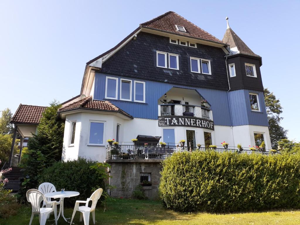 Villa Tannerhof في برونلاغ: منزل كبير من اللون الأزرق والأبيض مع طاولة وكراسي