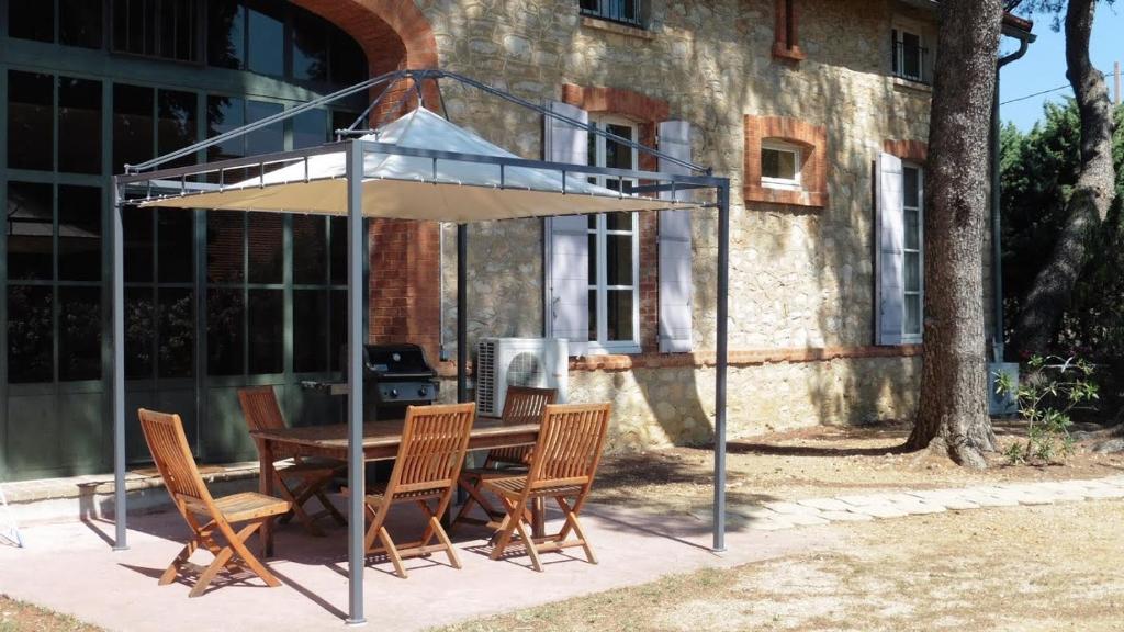 a table with chairs and an umbrella in front of a building at Les tamaris in La Londe-les-Maures