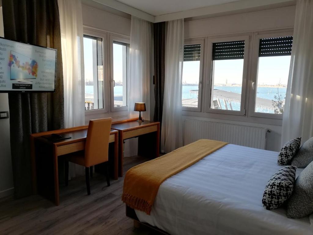 a hotel room with a bed and a desk and windows at Hotel Belvedere in Venice-Lido