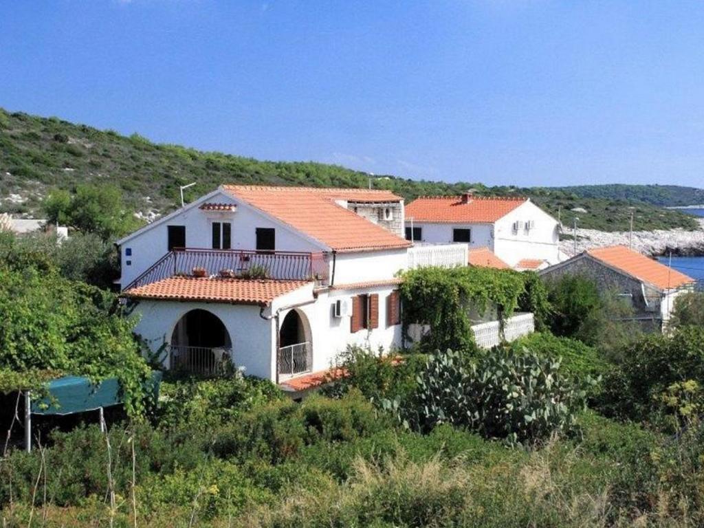 a white house with an orange roof on a hill at Apartments Katarina in Vis