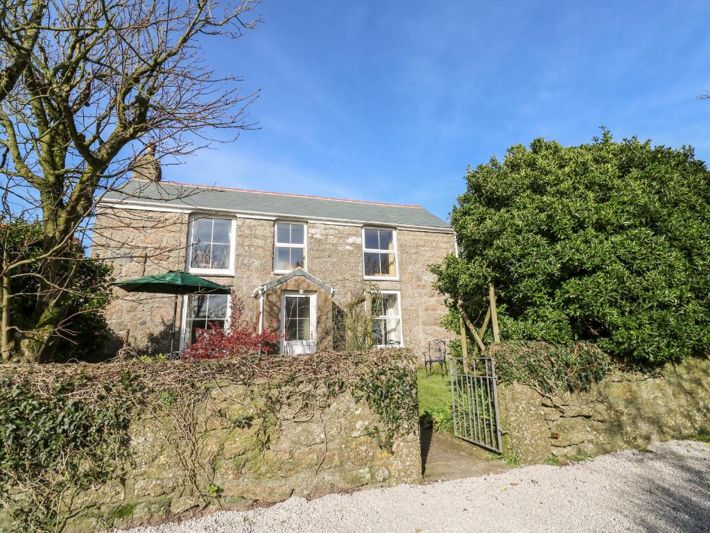 a brick house with a fence in front of it at Bosworlas Farm House in Penzance