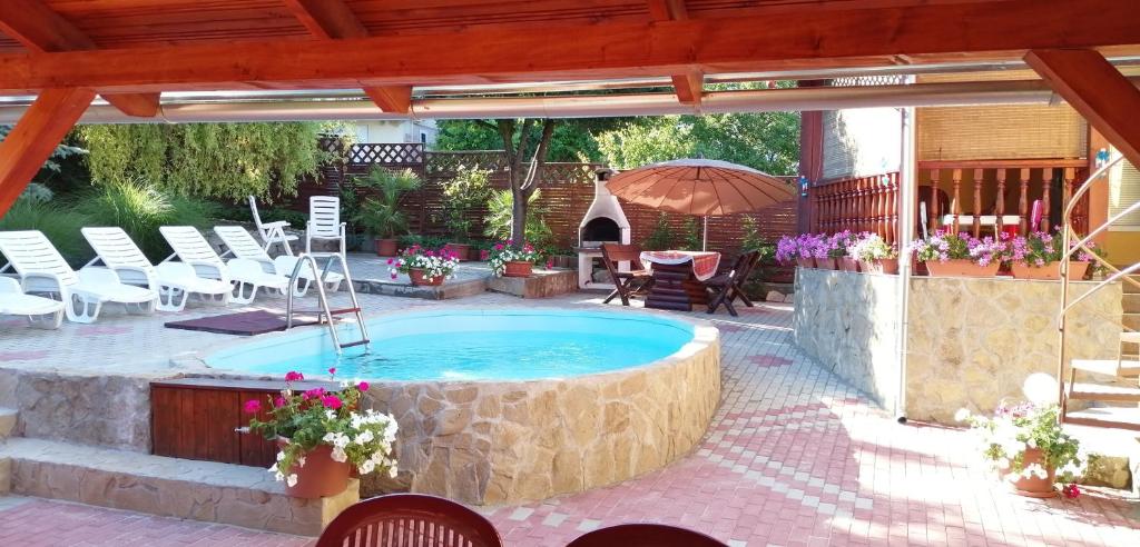 a swimming pool in a patio with chairs and an umbrella at Petra Vendégház in Fonyód