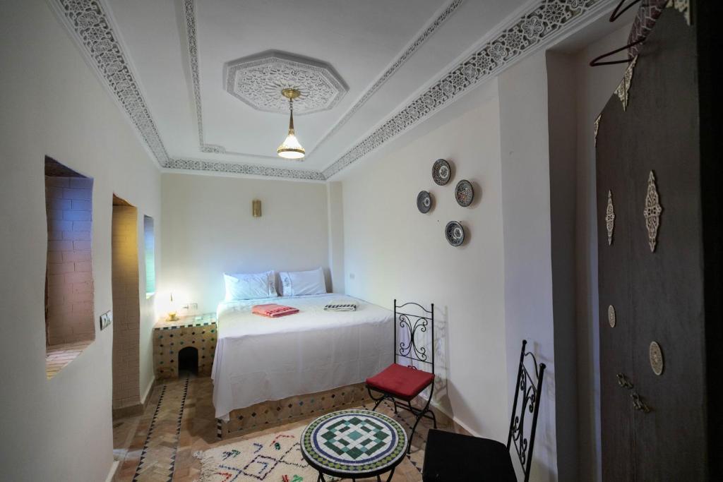 a bedroom with a white bed and a red chair at Riad Fez Unique in Fès