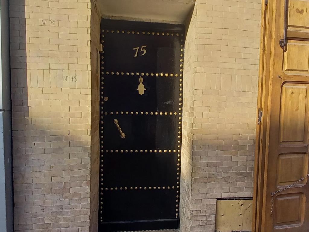 a black door with the number in a brick wall at studio Dar Rmila in Marrakesh