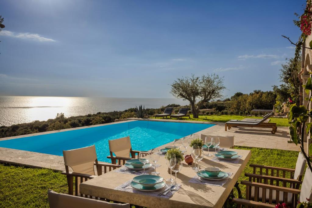 a dining table with chairs next to a swimming pool at Villa Comi in Mavráta