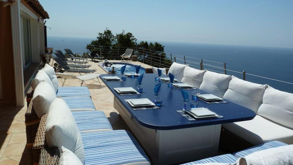une table bleue avec des coussins blancs sur un balcon dans l'établissement Le coin de paradis, à Saint-Raphaël