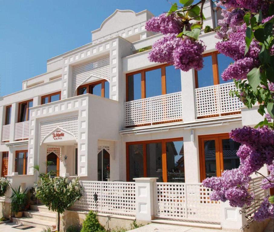 a white house with purple flowers in front of it at Amira Boutique Hotel Hévíz Wellness & Spa in Hévíz