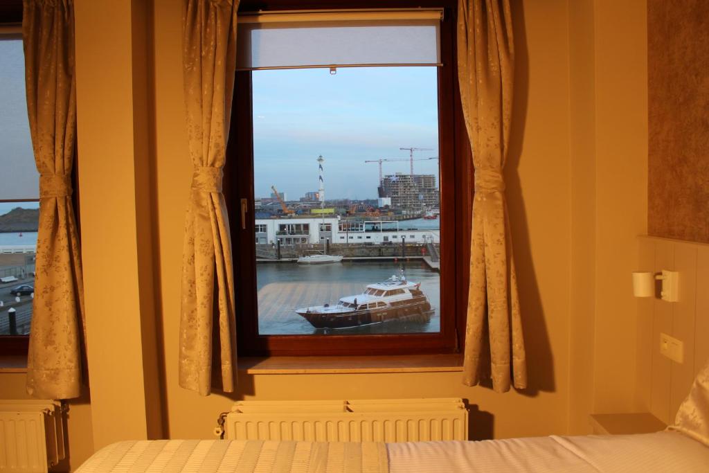 a bedroom with a window with a boat in the water at Hotel Rubens in Ostend