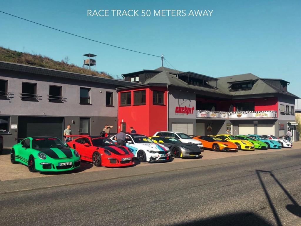 uma fila de carros coloridos estacionados em frente a um edifício em Guesthouse Cockpit em Adenau