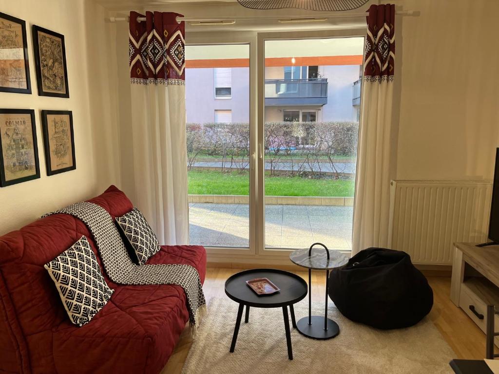 een woonkamer met een rode bank en een raam bij Le gîte de Marc - Parking privé gratuit + terrasse in Colmar