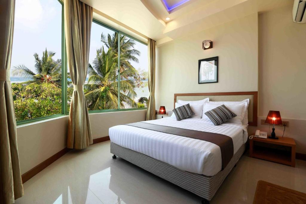 a bedroom with a large bed and a large window at Season Holidays at Hulhumale with Transfer in Hulhumale