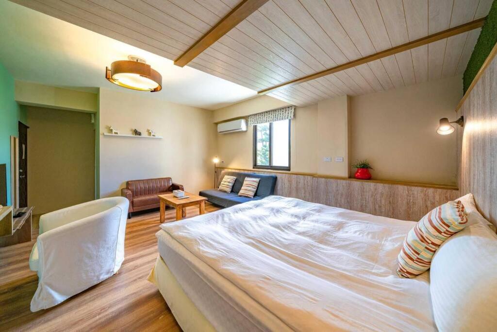 a bedroom with a large bed and a living room at Hejia B&amp;B in Hualien City