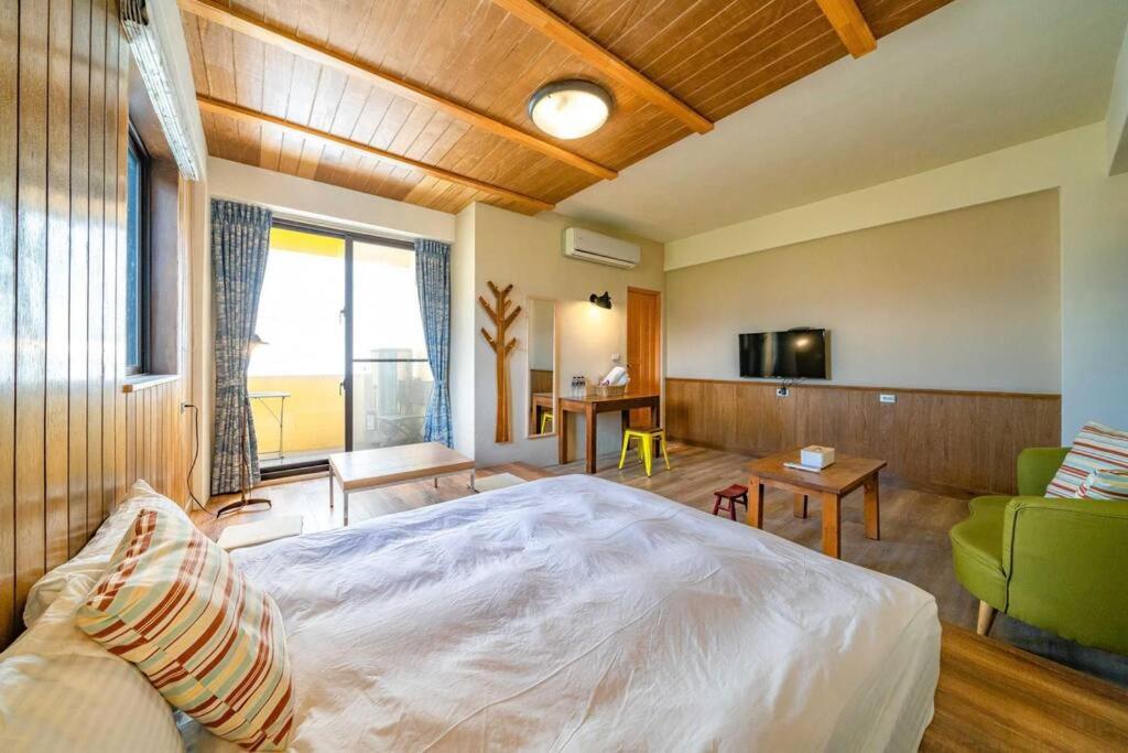 a bedroom with a large bed and a living room at Hejia B&amp;B in Hualien City