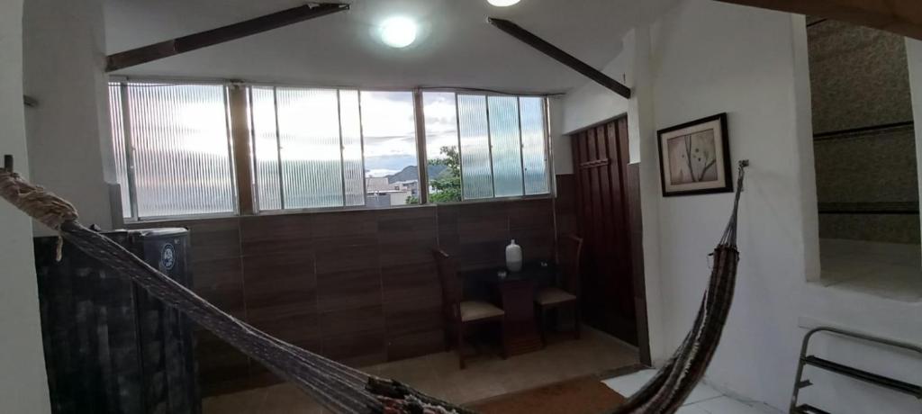 hamaca en una habitación con mesa y ventanas en Casa do Bill Recreio, en Río de Janeiro