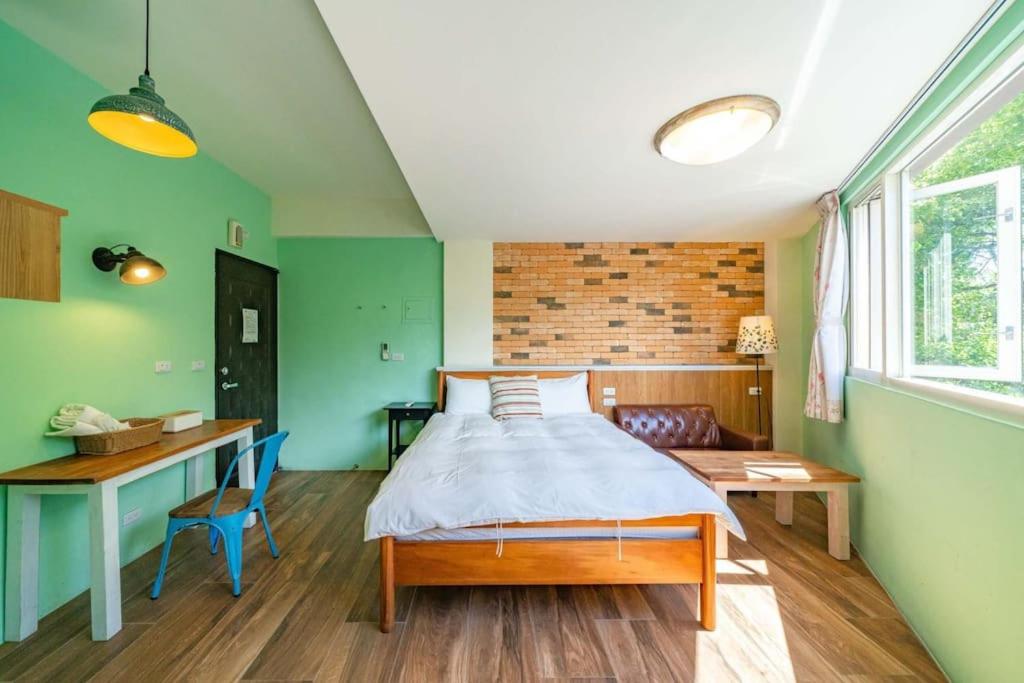 a bedroom with green walls and a bed and a desk at Hejia B&amp;B in Hualien City