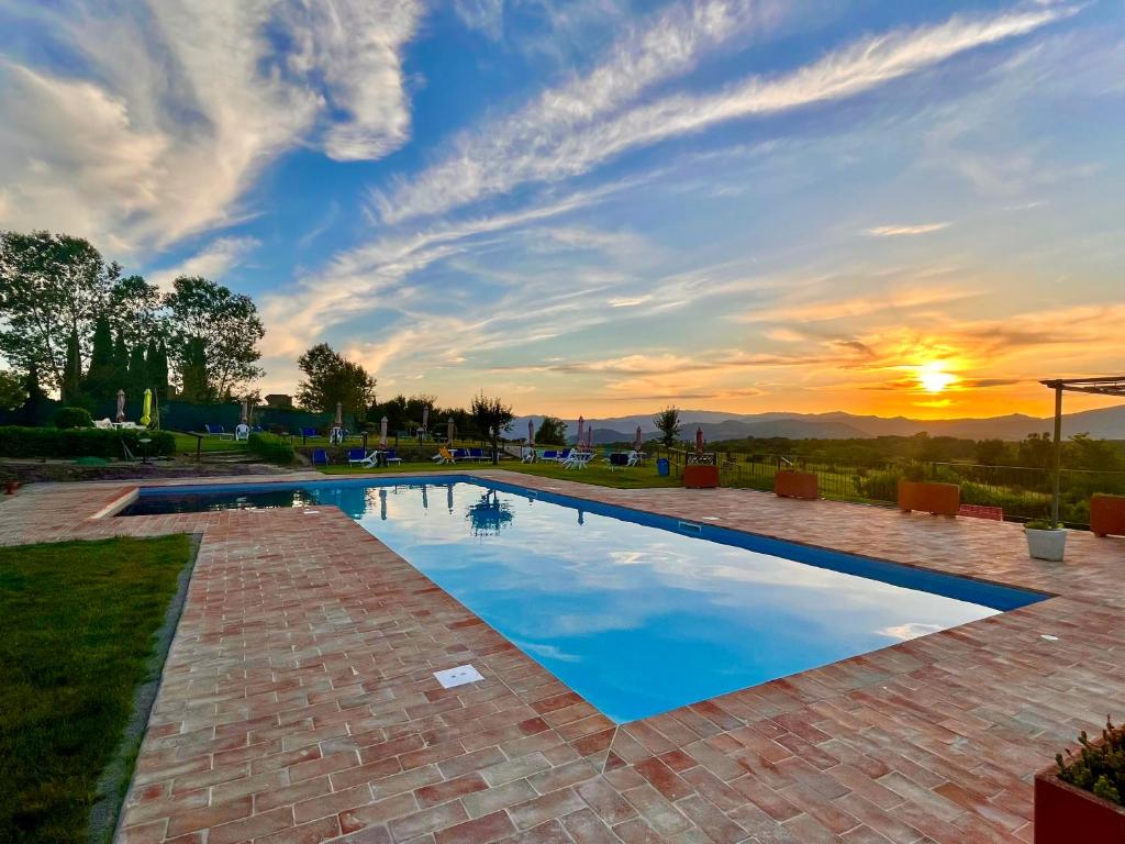 a swimming pool with a sunset in the background at "Villa Bizzi" in Monte Castelli
