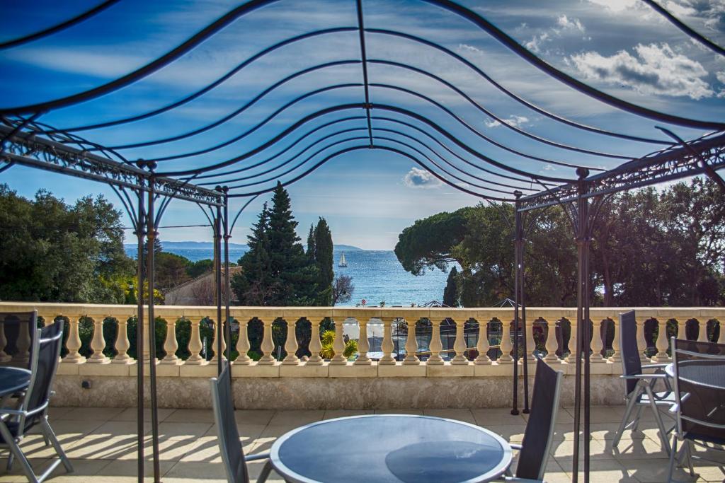 una mesa y sillas en un balcón con vistas al océano en La Résidence du Cap en Le Lavandou