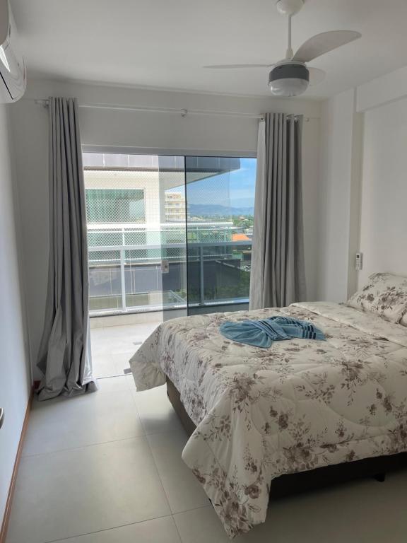 a bedroom with a bed and a large window at Temporada Cabo Frio - Braga in Cabo Frio