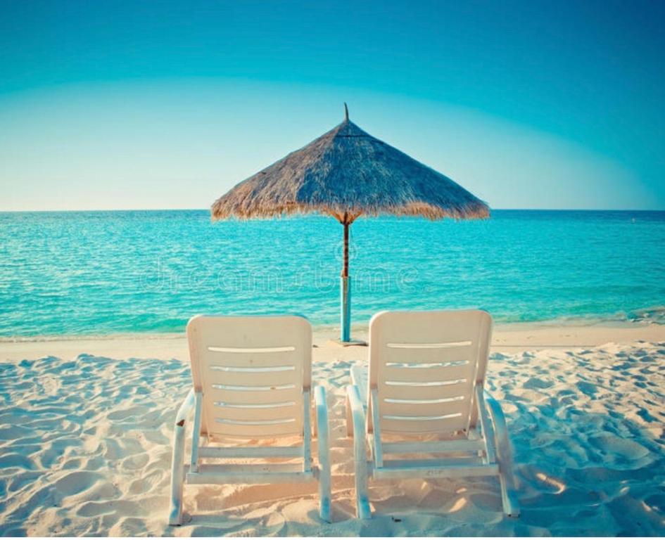 twee stoelen en een parasol op het strand bij Moriani Les Marines de Moriani Plage in San-Nicolao