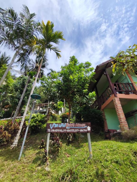 a sign in front of a building with palm trees at Chalisa Bukit House Lanta in Ko Lanta