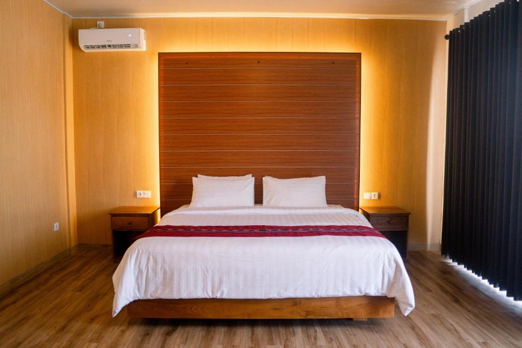 a bedroom with a large bed with a wooden headboard at Christika Homestay in Labuan Bajo