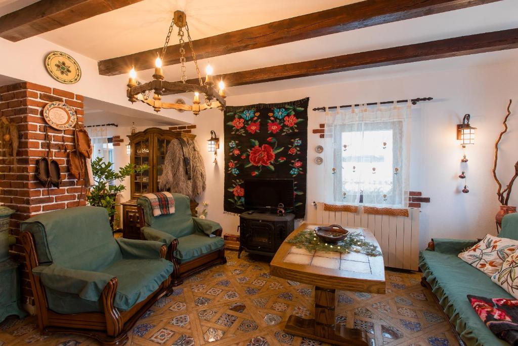 ein Wohnzimmer mit einem Sofa, Stühlen und einem TV in der Unterkunft Casa cu Cerdac in Nucşoara
