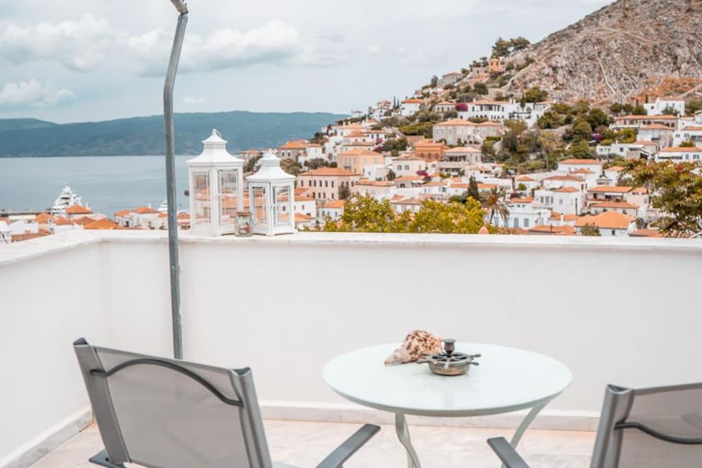 a table and chairs on a balcony with a view of a city at SUNSET STUDIO - HYDRA DREAM HOUSES in Hydra
