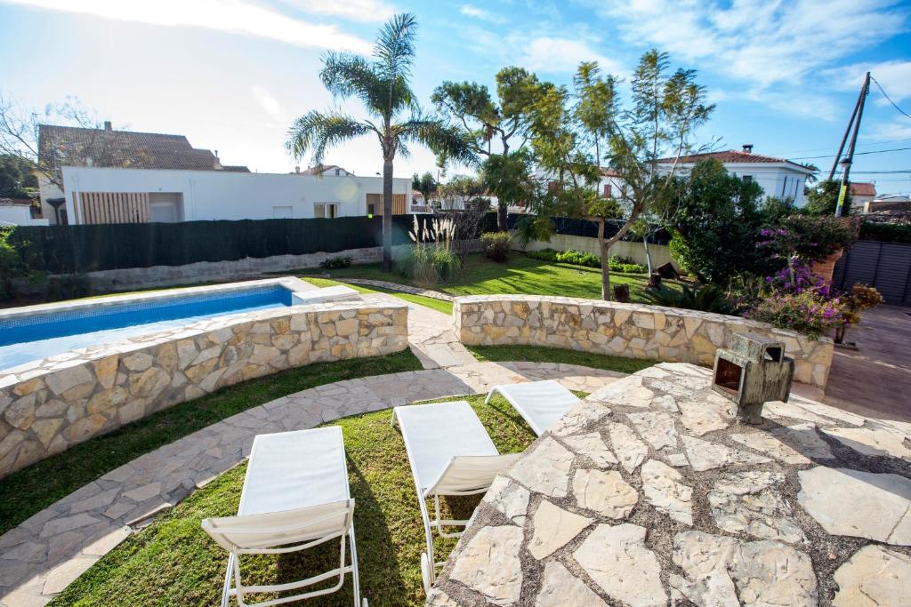einen Garten mit zwei Stühlen und einem Pool in der Unterkunft Villa Parets de Sucre in Les Cases d'Alcanar