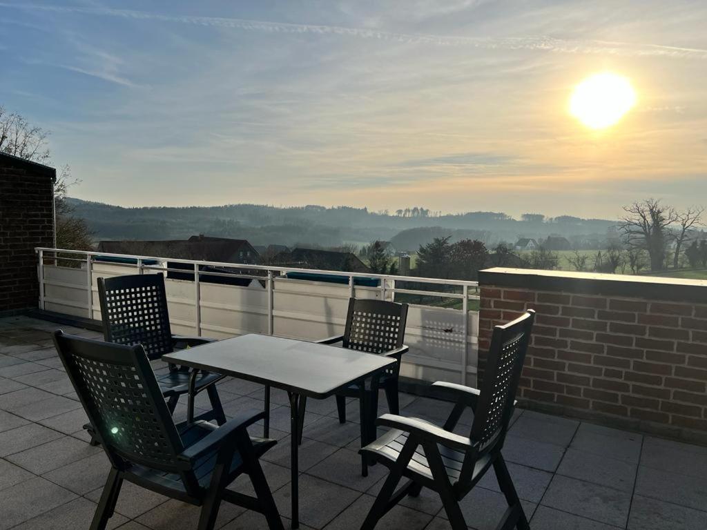 a table and chairs on a patio with the sun setting at Wiehengebirgs Fernblick App 4 in Bad Essen