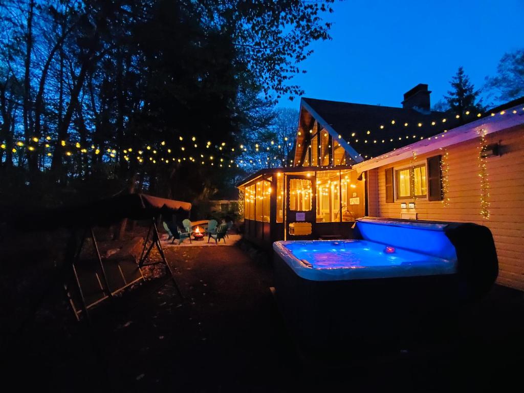 a house with a lit up backyard at night at 1 Minute to Pool & Beach, Spacious Getaway, AC, Hot tub, Game room in Pocono Country Place