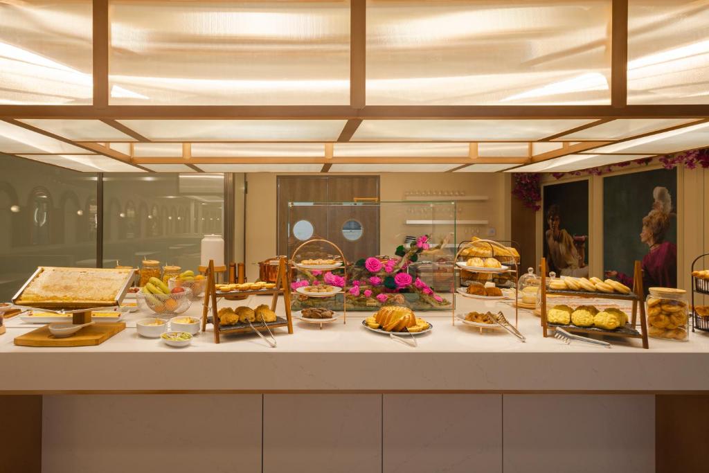 A buffet counter displaying pastries, bread, fruit, and plated breakfast items under warm illuminated panels.