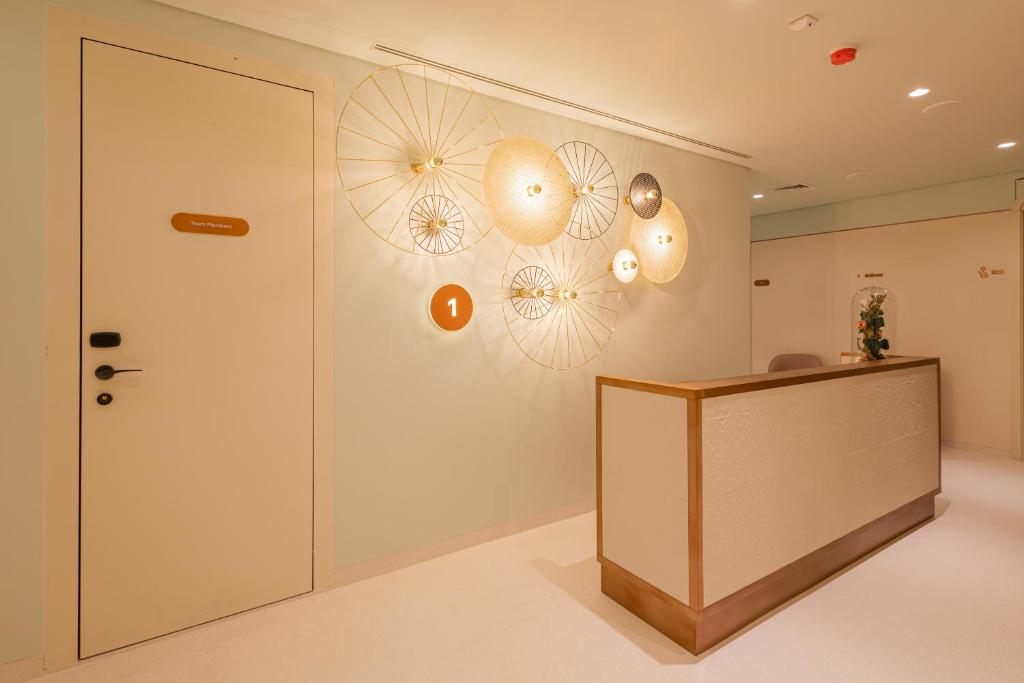 A compact reception area with a small desk, decorative wall lights and a numbered doorway.