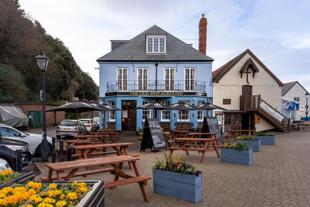a blue building with tables and umbrellas in front of it at The Old Ship Aground in Minehead