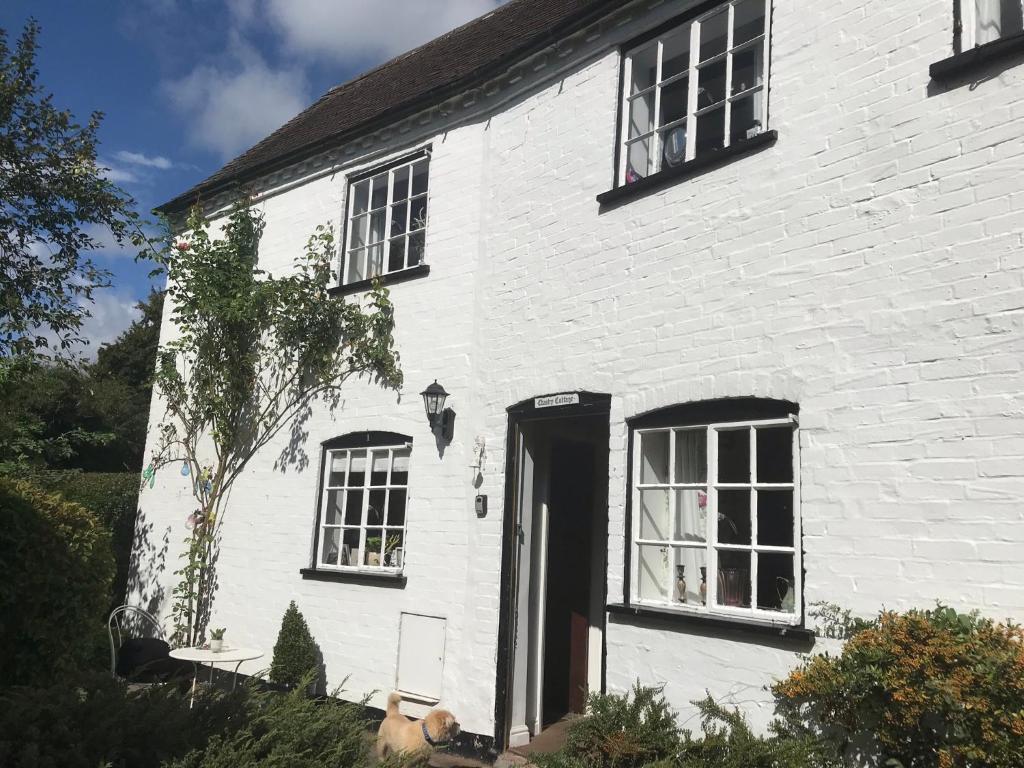 a white brick house with a black door and windows at Idyllic Stratford upon Avon cottage in Shottery