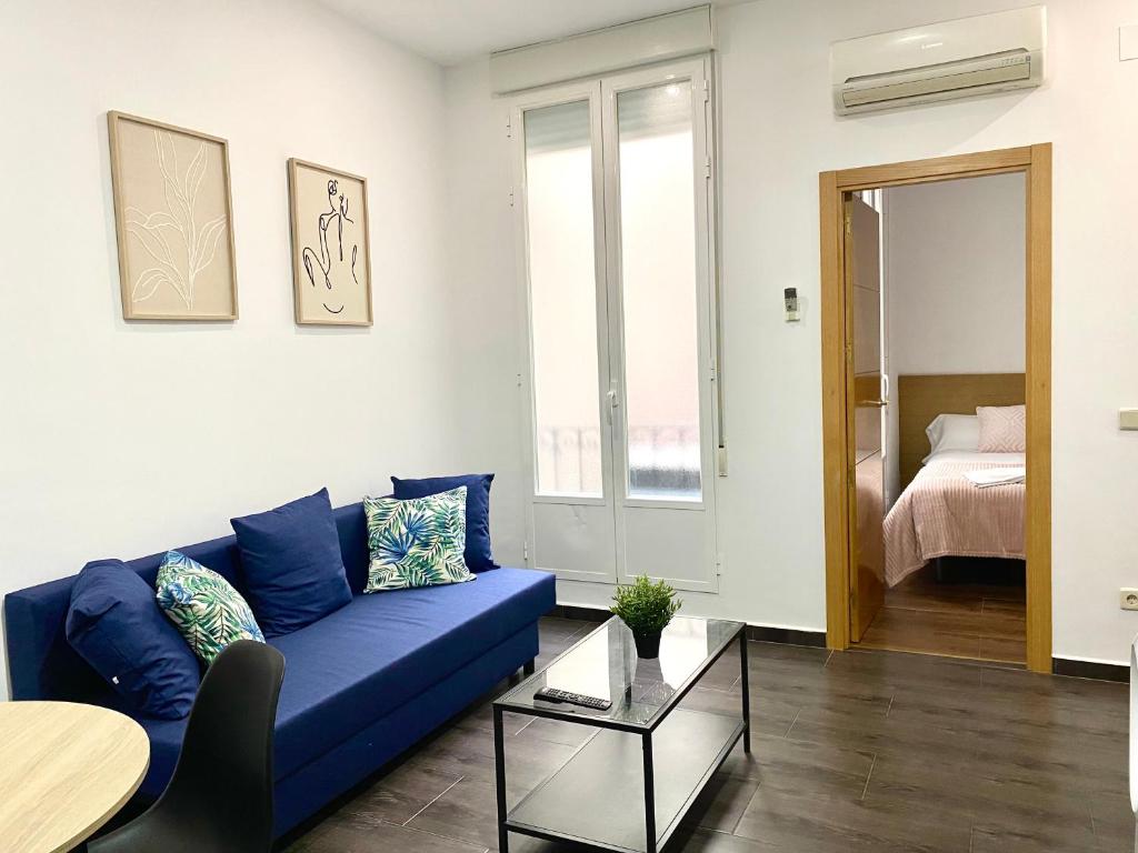 een woonkamer met een blauwe bank en een tafel bij Apartamentos Fuencarral II in Madrid