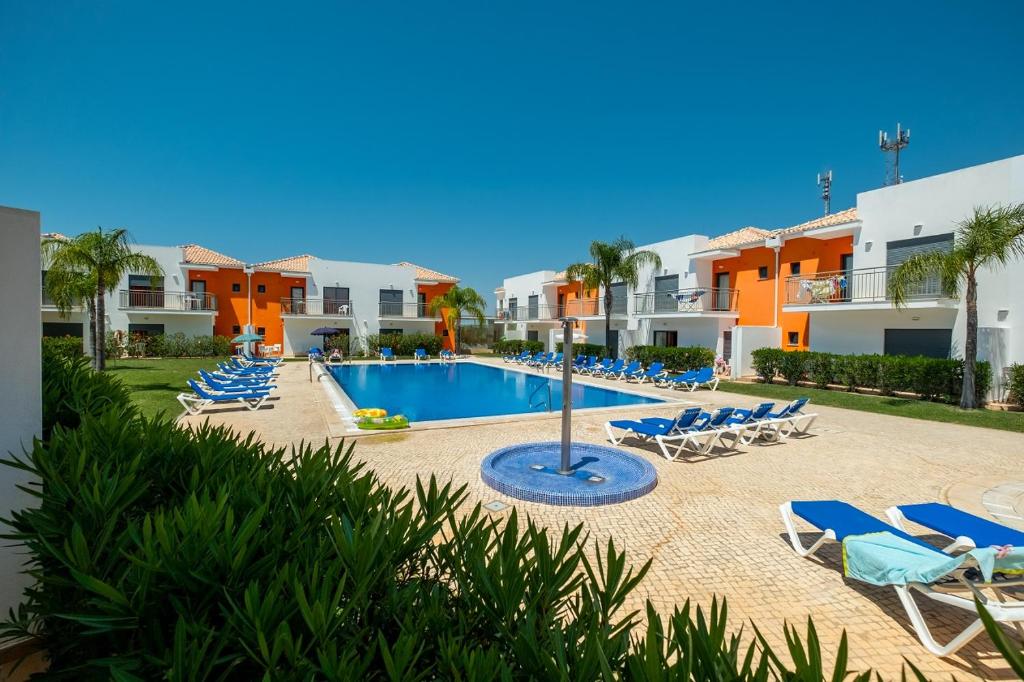 uma vista para a piscina no resort com espreguiçadeiras em Jardins de Pêra em Pêra