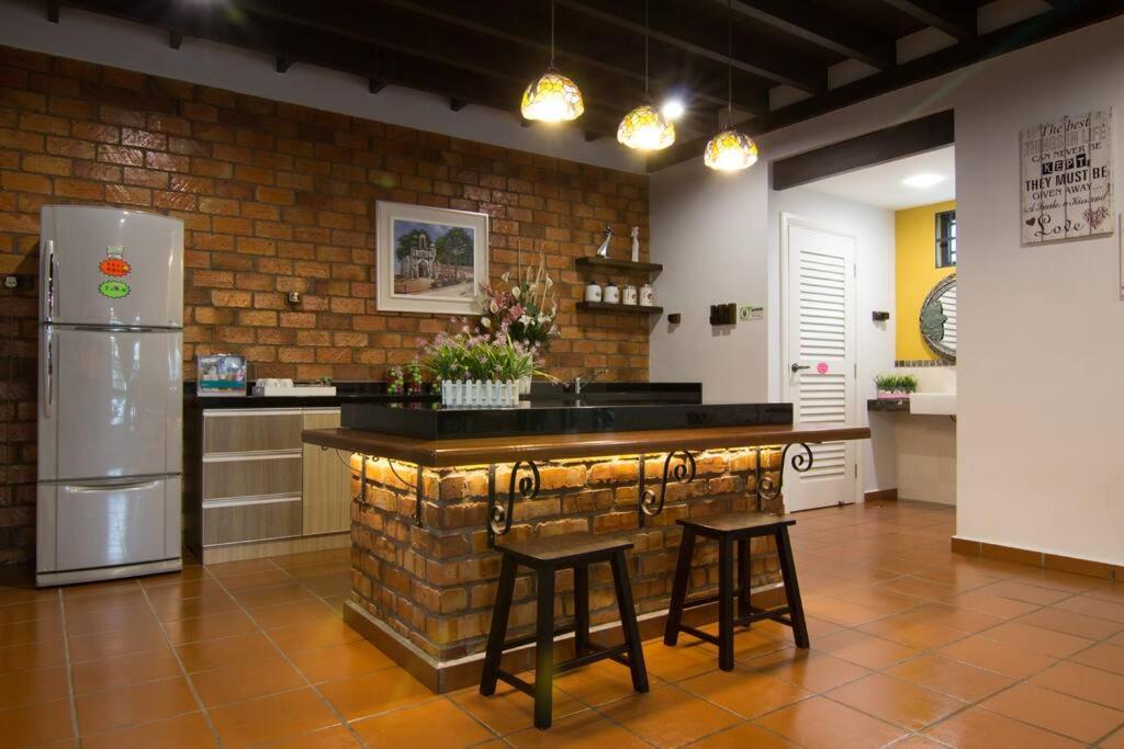 a kitchen with a bar with stools and a refrigerator at Harmonia Homestay in Melaka