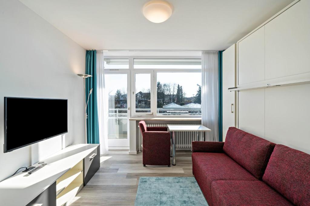 sala de estar con sofá rojo y TV en Huber Living Basic 206, en Germering