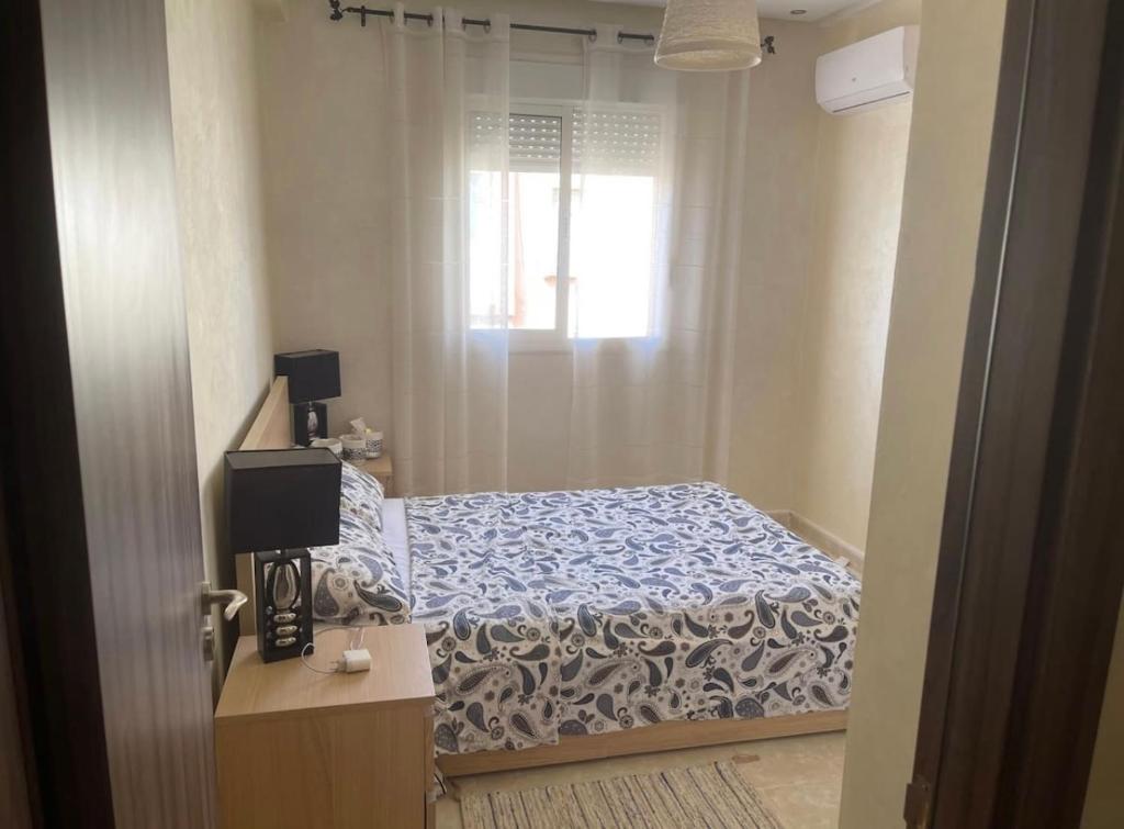 niewielka sypialnia z łóżkiem i oknem w obiekcie Appartement en résidence avec parking w Marakeszu