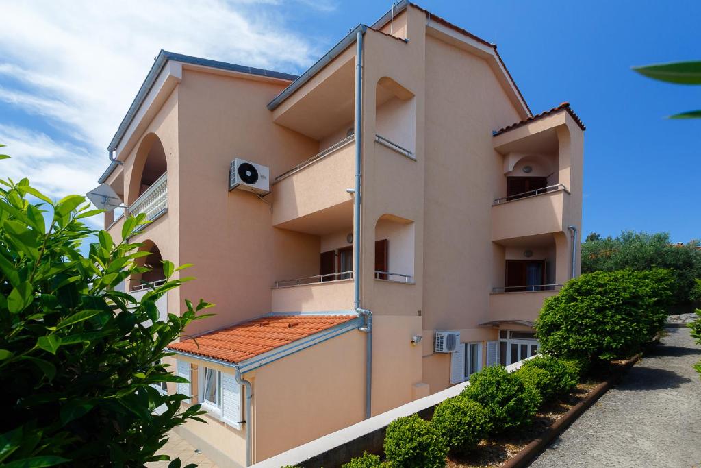 un immeuble d'appartements avec balcon et buissons dans l'établissement Adrijana, à Krk
